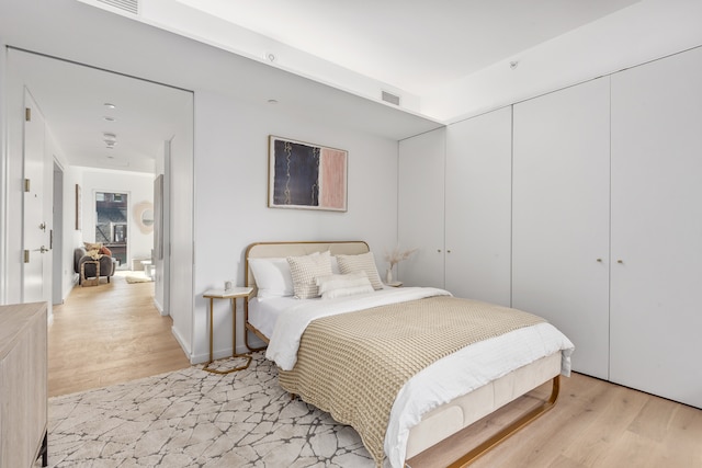 bedroom featuring a closet, visible vents, and light wood finished floors