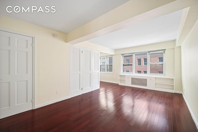 spare room featuring baseboards and wood finished floors