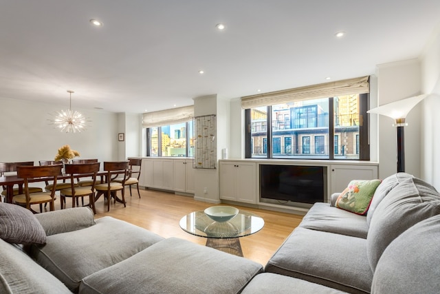 living room with a notable chandelier, crown molding, and light hardwood / wood-style floors