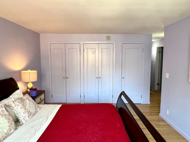 bedroom featuring multiple closets and light hardwood / wood-style floors