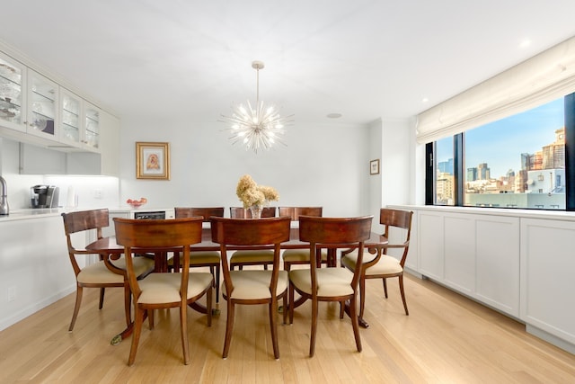 dining area with recessed lighting, a notable chandelier, light wood-style flooring, and a city view