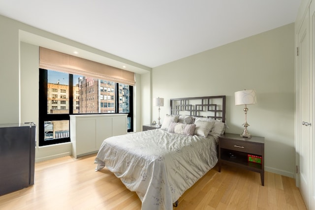 bedroom featuring black fridge and light hardwood / wood-style floors