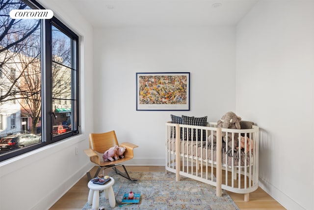 bedroom with light hardwood / wood-style flooring and a crib