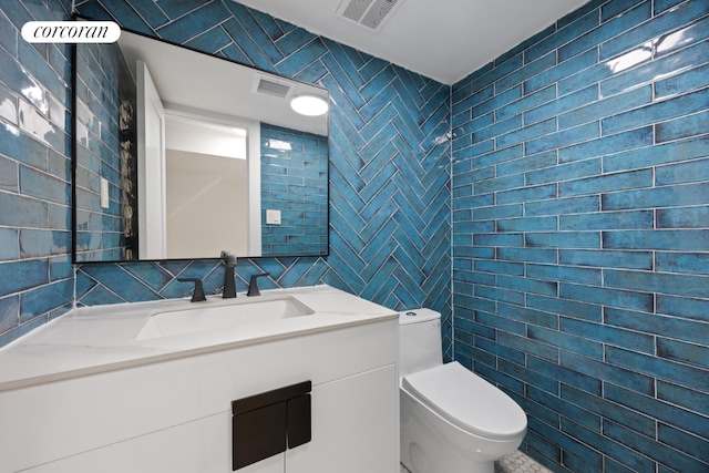 bathroom with toilet, tile walls, and vanity