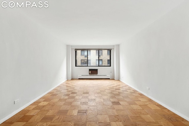 unfurnished room with a baseboard heating unit and light parquet floors