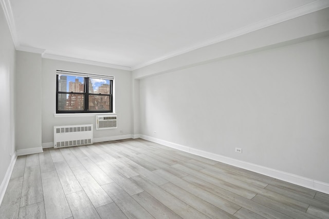 spare room with radiator heating unit, a wall mounted AC, ornamental molding, wood finished floors, and baseboards