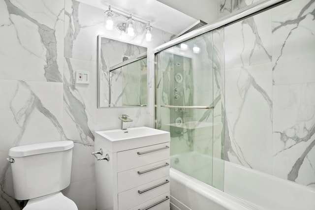 full bathroom featuring toilet, enclosed tub / shower combo, tile walls, and vanity