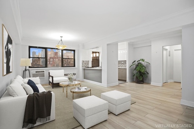 living room featuring light wood-style floors, baseboards, ornamental molding, and an AC wall unit