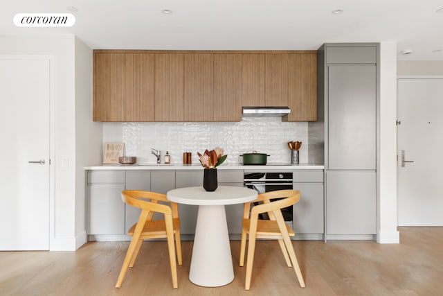 kitchen with tasteful backsplash, light hardwood / wood-style floors, and oven