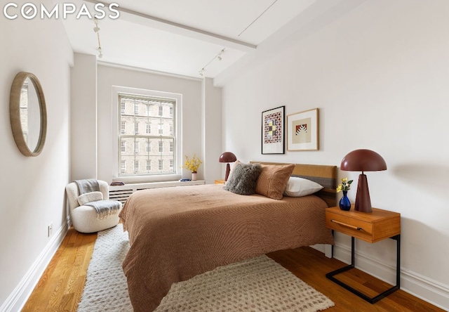 bedroom featuring light hardwood / wood-style flooring and beam ceiling