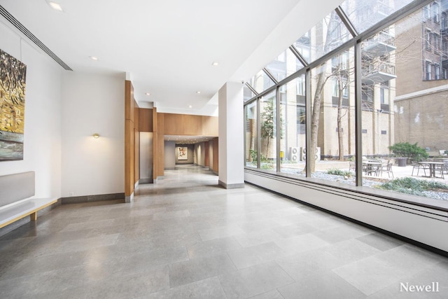 unfurnished living room featuring a baseboard heating unit, recessed lighting, and baseboards