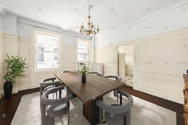 dining room with a notable chandelier, ornamental molding, parquet flooring, and a decorative wall