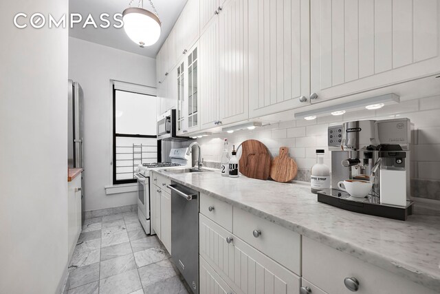 kitchen featuring light stone counters, white cabinetry, decorative backsplash, and stainless steel appliances