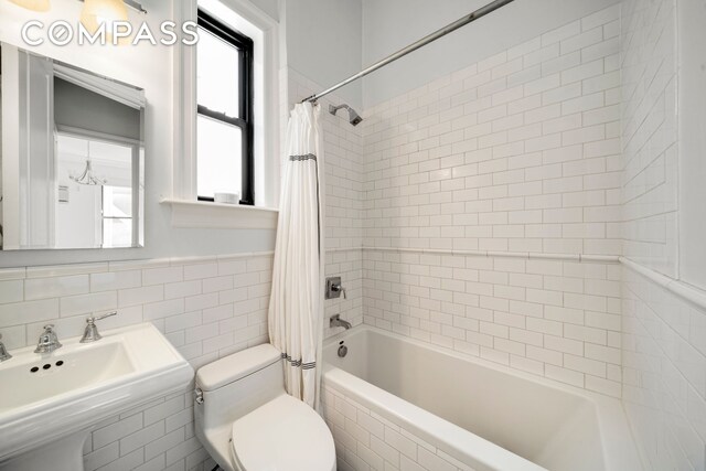 full bathroom with sink, tile walls, toilet, and shower / bath combination with curtain