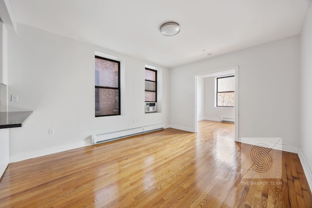 unfurnished room featuring baseboard heating, cooling unit, baseboards, and wood-type flooring