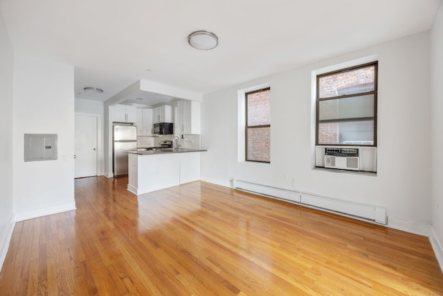 unfurnished living room with light wood-style flooring, electric panel, cooling unit, baseboards, and baseboard heating