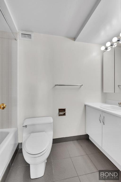 bathroom featuring toilet, vanity, and tile patterned flooring