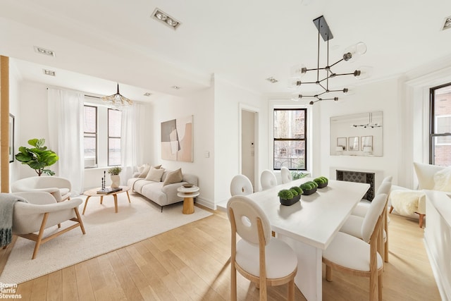 dining space with crown molding, an inviting chandelier, baseboards, and light wood-style floors