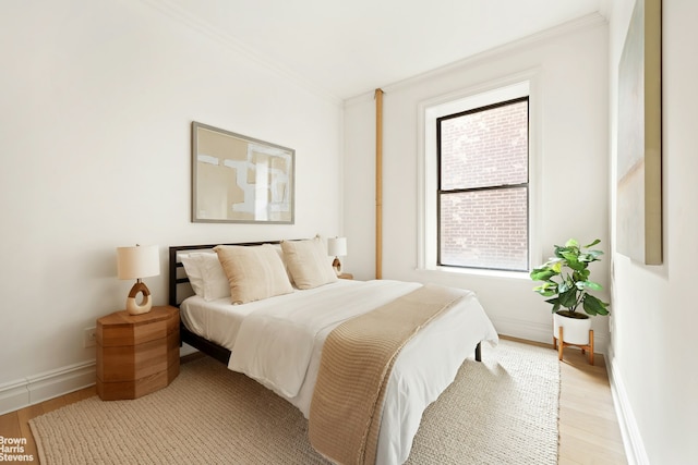 bedroom with baseboards, light wood-style floors, and crown molding