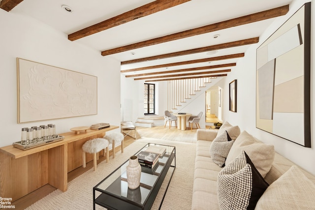 living area featuring beamed ceiling and stairway