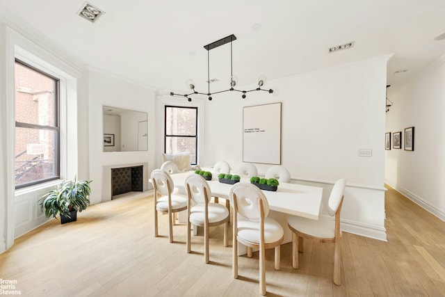 dining space featuring baseboards, light wood-type flooring, a wealth of natural light, and crown molding