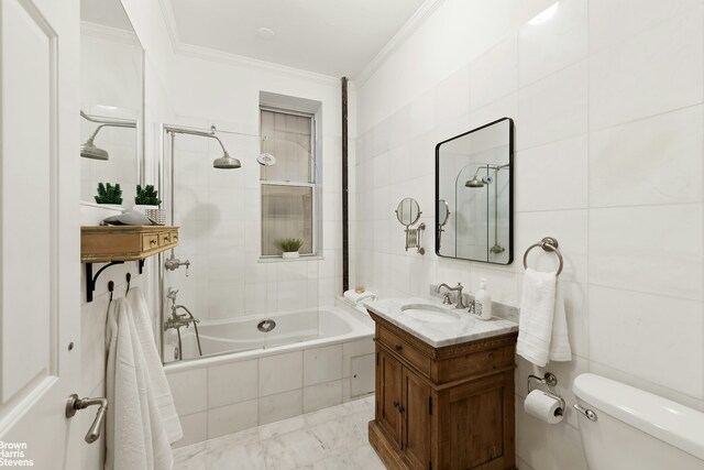 bathroom with vanity, crown molding, toilet, tiled shower / bath, and tile walls