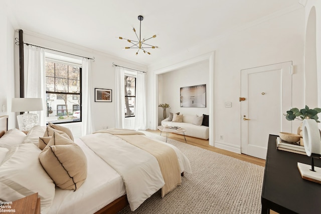 bedroom with an inviting chandelier, crown molding, baseboards, and wood finished floors