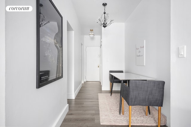 corridor with dark wood-type flooring and a notable chandelier