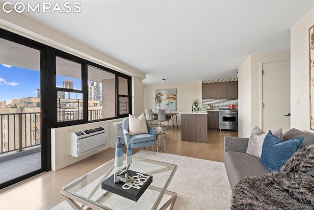 living room featuring light wood-type flooring and an AC wall unit