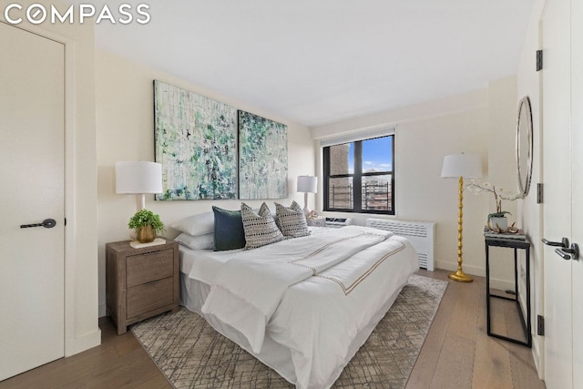 bedroom with hardwood / wood-style flooring and radiator heating unit