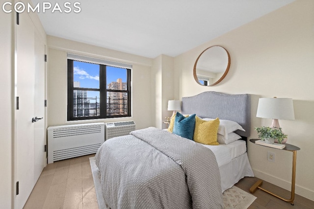 bedroom featuring a wall mounted air conditioner, heating unit, and light wood-type flooring