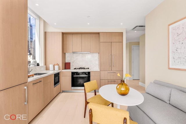 kitchen featuring tasteful backsplash, sink, black microwave, light brown cabinets, and wall oven