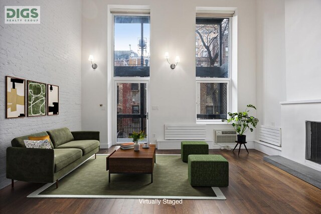 living room with dark wood-type flooring and an AC wall unit