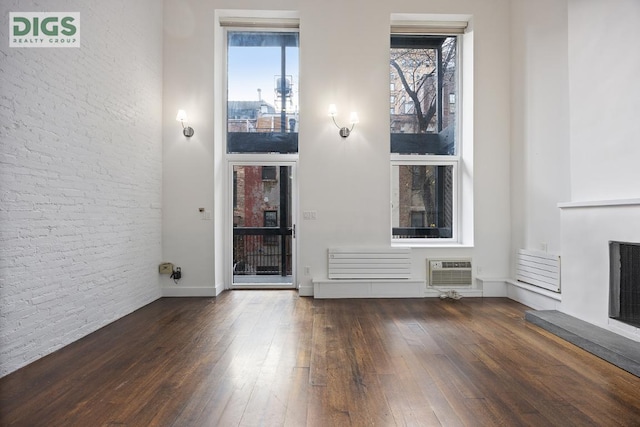 unfurnished living room with a fireplace, dark hardwood / wood-style floors, and a wall mounted air conditioner