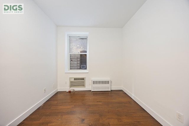 empty room featuring dark wood-type flooring, radiator heating unit, and a wall unit AC