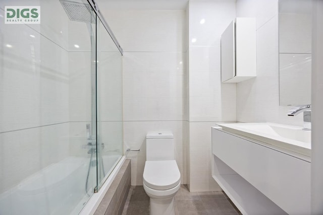 full bathroom with tile walls, toilet, vanity, and combined bath / shower with glass door