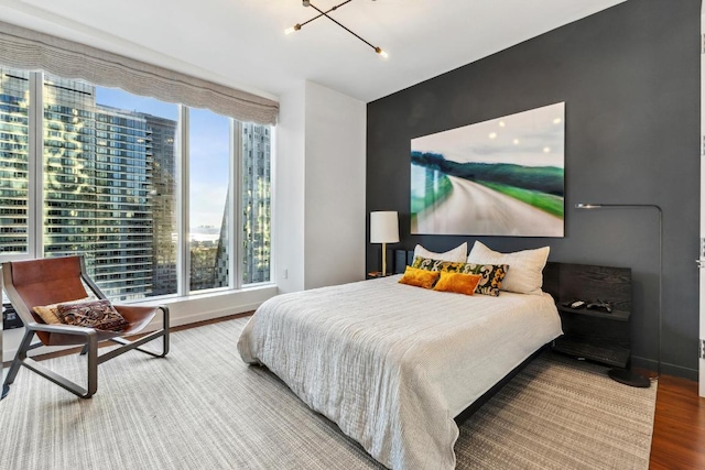 bedroom with a chandelier, wood-type flooring, and multiple windows