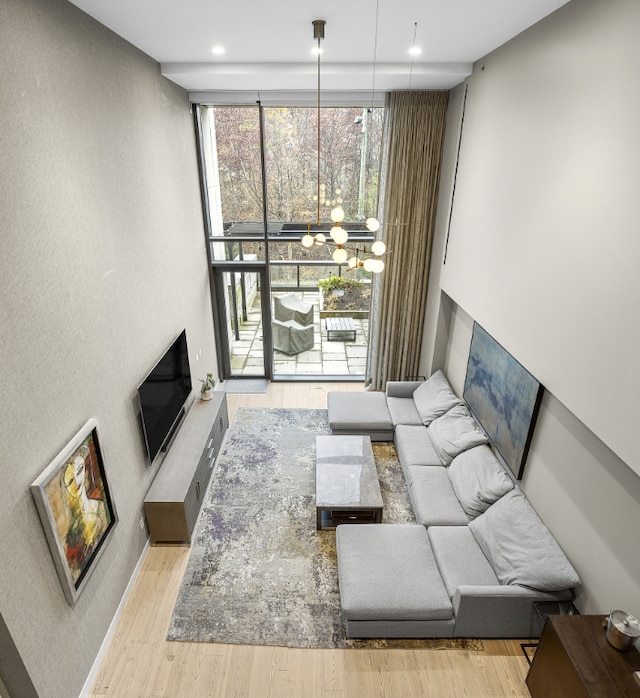 living area with expansive windows, baseboards, light wood finished floors, and an inviting chandelier