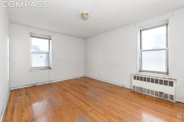 unfurnished living room with radiator heating unit and hardwood / wood-style flooring