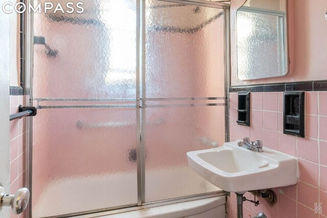 kitchen with white cabinets, sink, stainless steel gas range, and radiator heating unit