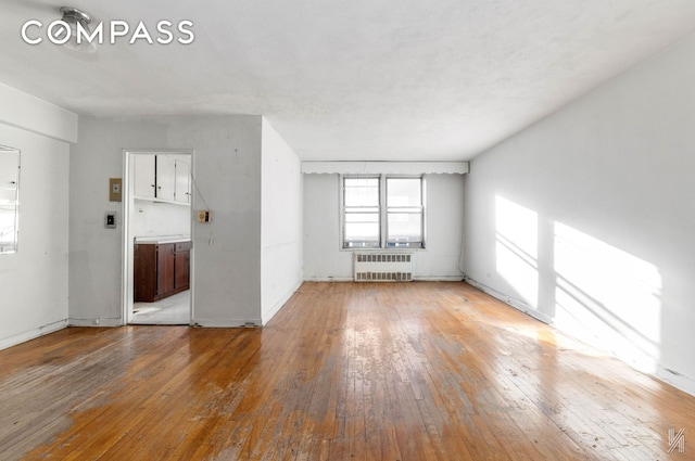 unfurnished living room featuring hardwood / wood-style floors and radiator heating unit