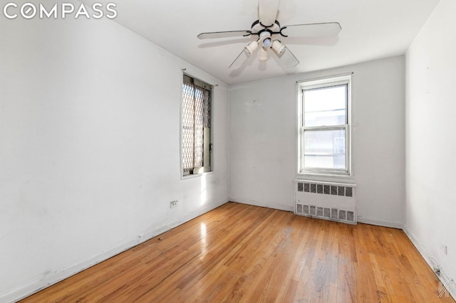 unfurnished room with ceiling fan, light wood-type flooring, and radiator heating unit