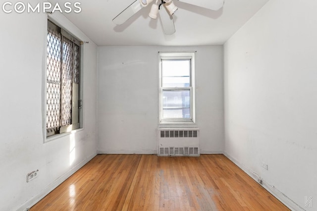 unfurnished room with ceiling fan, light hardwood / wood-style floors, and radiator