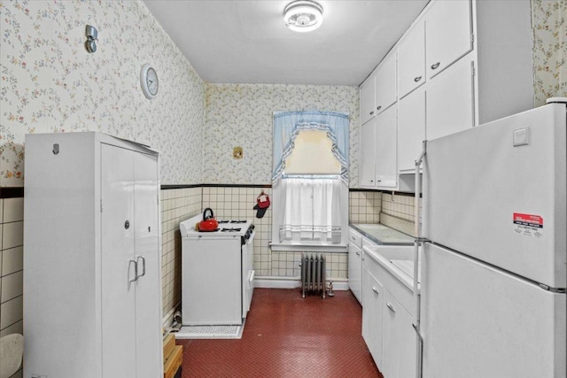 kitchen with white cabinetry, backsplash, radiator heating unit, white refrigerator, and washer / clothes dryer