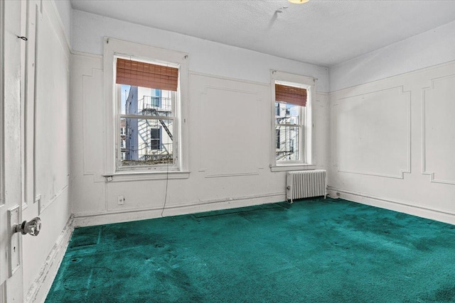 unfurnished room featuring carpet flooring, radiator, and a textured ceiling