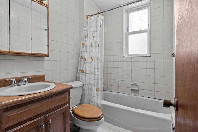 bathroom featuring tile patterned floors, toilet, tile walls, shower / tub combo, and vanity