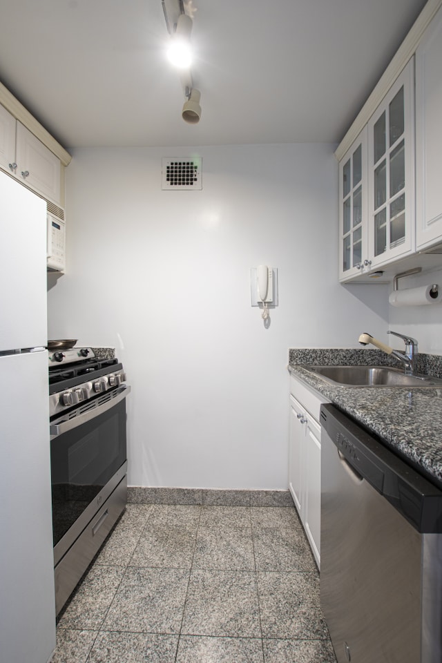 kitchen featuring dark countertops, visible vents, appliances with stainless steel finishes, granite finish floor, and a sink