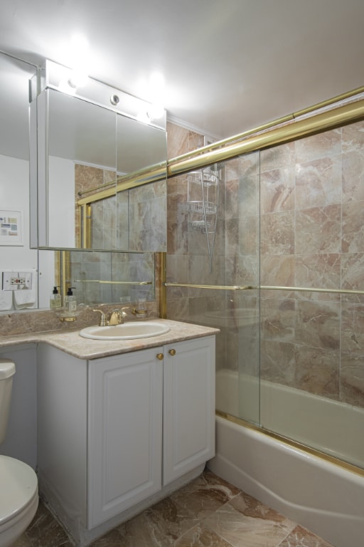 full bathroom featuring vanity, toilet, combined bath / shower with glass door, and marble finish floor