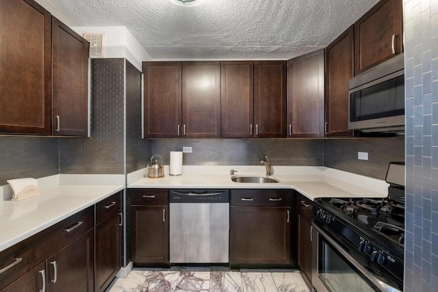 kitchen featuring sink, dark brown cabinets, stainless steel appliances, tasteful backsplash, and a textured ceiling