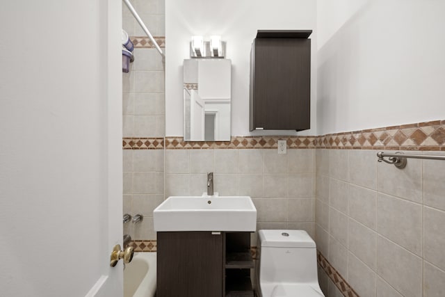 bathroom featuring toilet, tile walls, wainscoting, and a sink